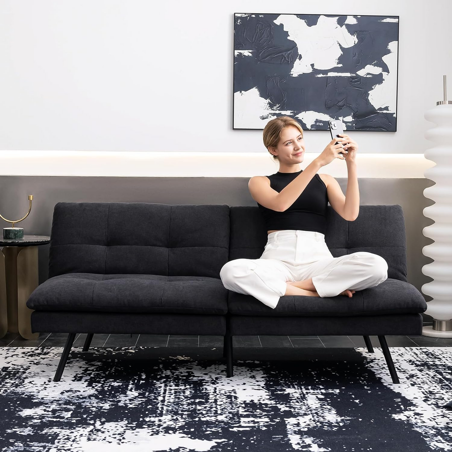 Couch Bed Futon Sleeper Sofa for Living Room | Black Memory Foam from AHF Depot - Black fabric futon with split back adjustment displayed in a modern living room scene with a woman sitting on the couch. .