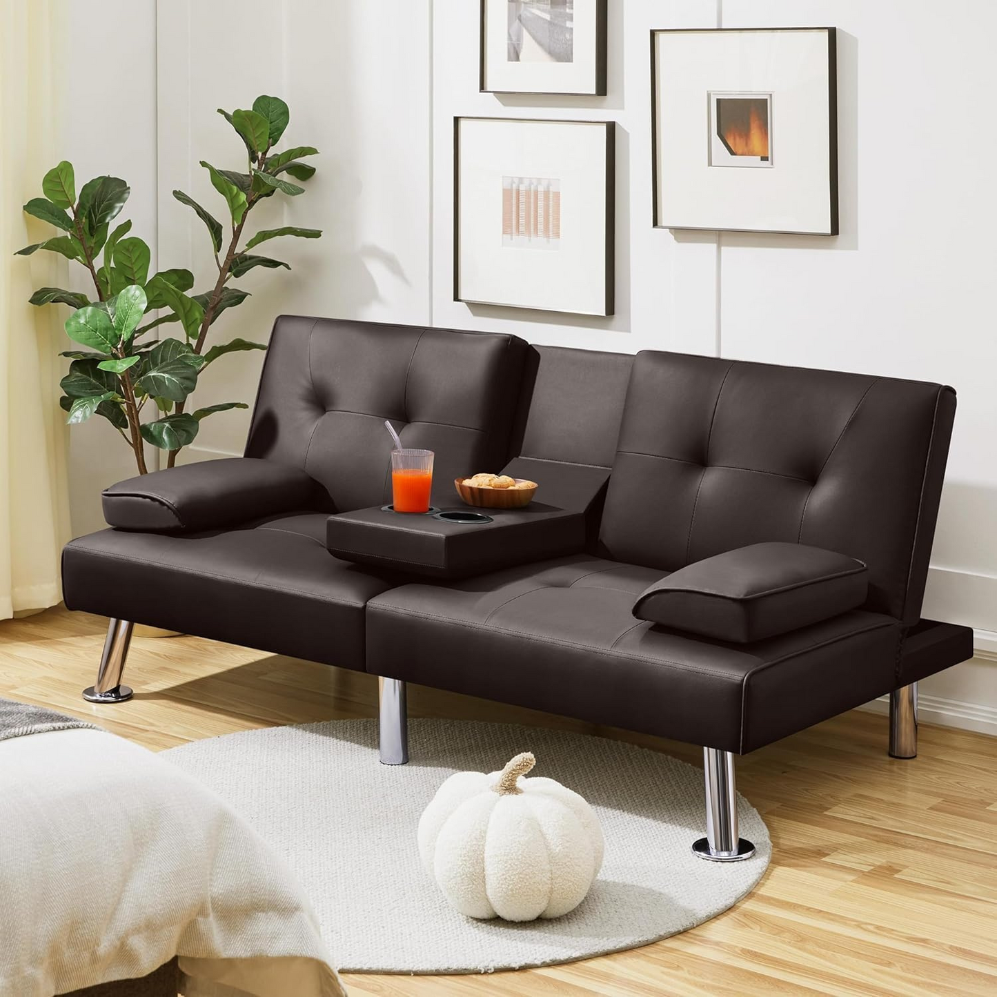 Couch Bed Futon Sleeper Sofa for Living Room | Brown Faux Leather from AHF Depot - Brown leather futon with center cupholders displayed against a modern living room scene, positioned beside and indoor plant.