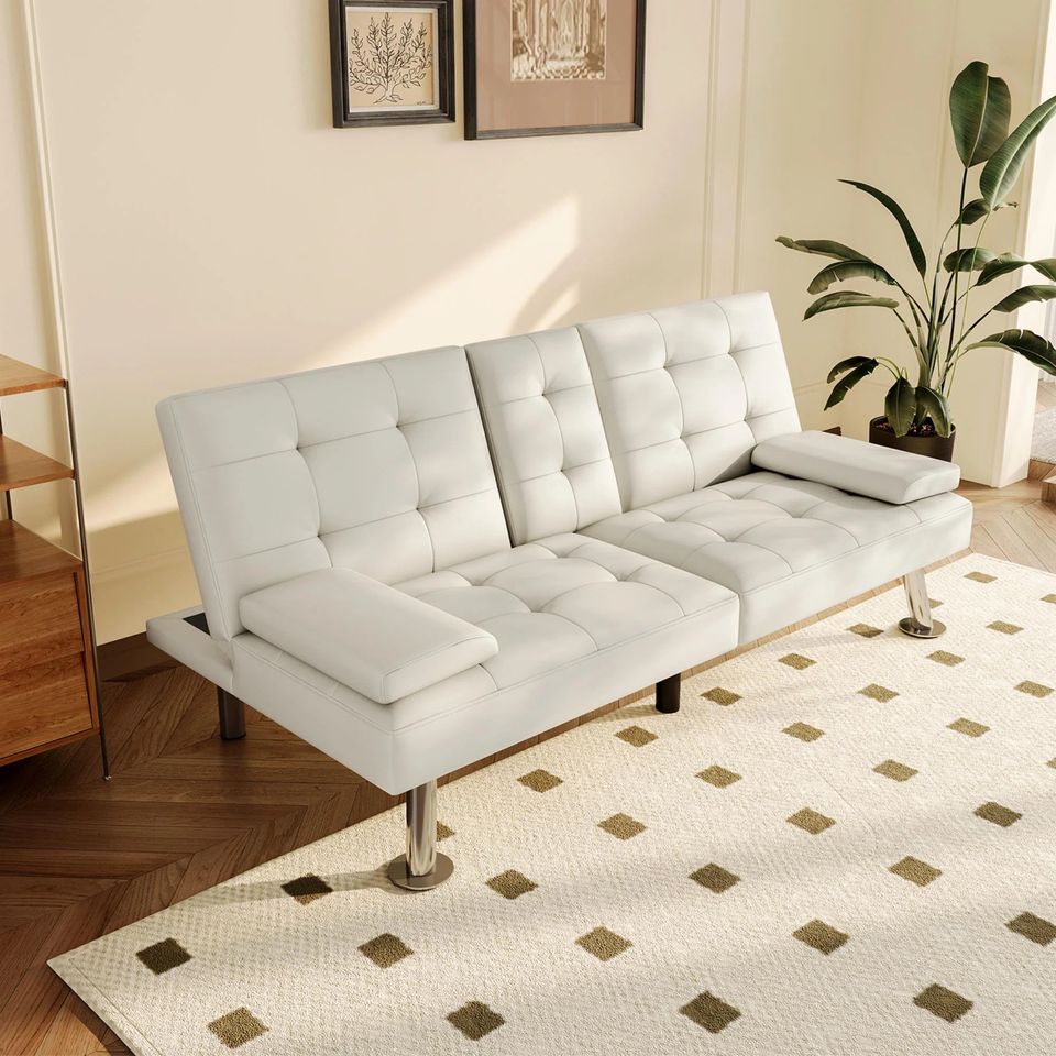 Couch Bed Futon Sleeper Sofa for Living Room | White Faux Leather from AHF Depot - White leather futon with center cupholders displayed beside oak end table in a modern living room scene, beside an interior plant. 