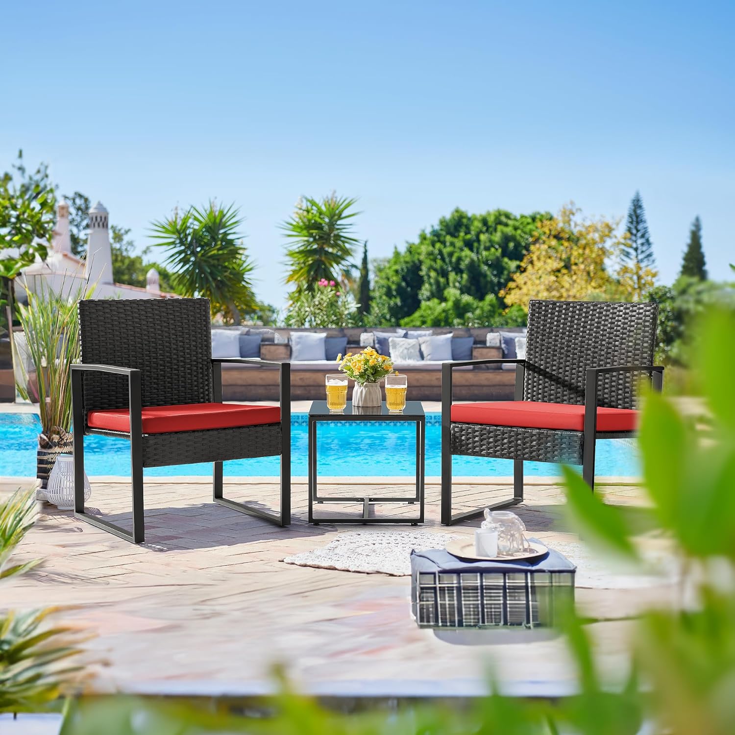 Outdoor Patio Chairs and Table Set | Black/Red from AHF Depot - Modern black frame patio conversation set with red cushions and small glass top table adorned with two glasses of iced tea, set amidst a sunny outdoor poolside scene.