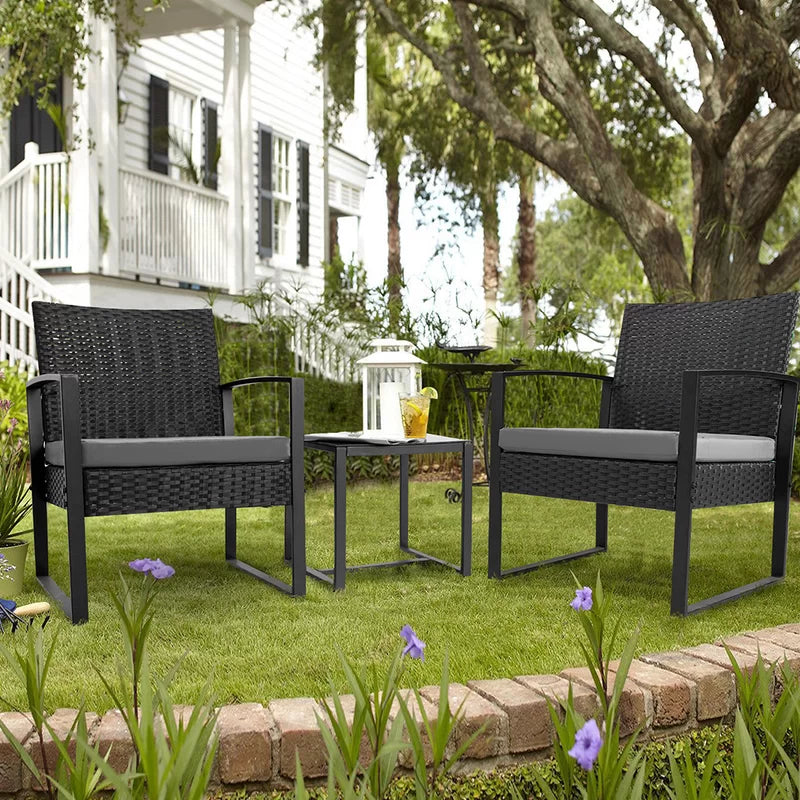 Outdoor Patio Chairs and Table Set | Black/Grey from AHF Depot - Modern black frame patio conversation set with grey cushions and small glass top table adorned with a glass of iced tea, set amidst a sunny outdoor front yard scene.