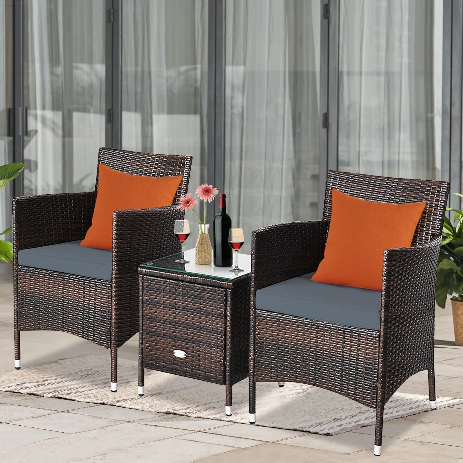 Outdoor Patio Chairs and Table Set | Brown/Grey from AHF Depot - Modern brown rattan frame patio conversation set with grey cushions and small glass top table adorned with a bottle and glasses of wine, set amidst a sunny outdoor patio scene.