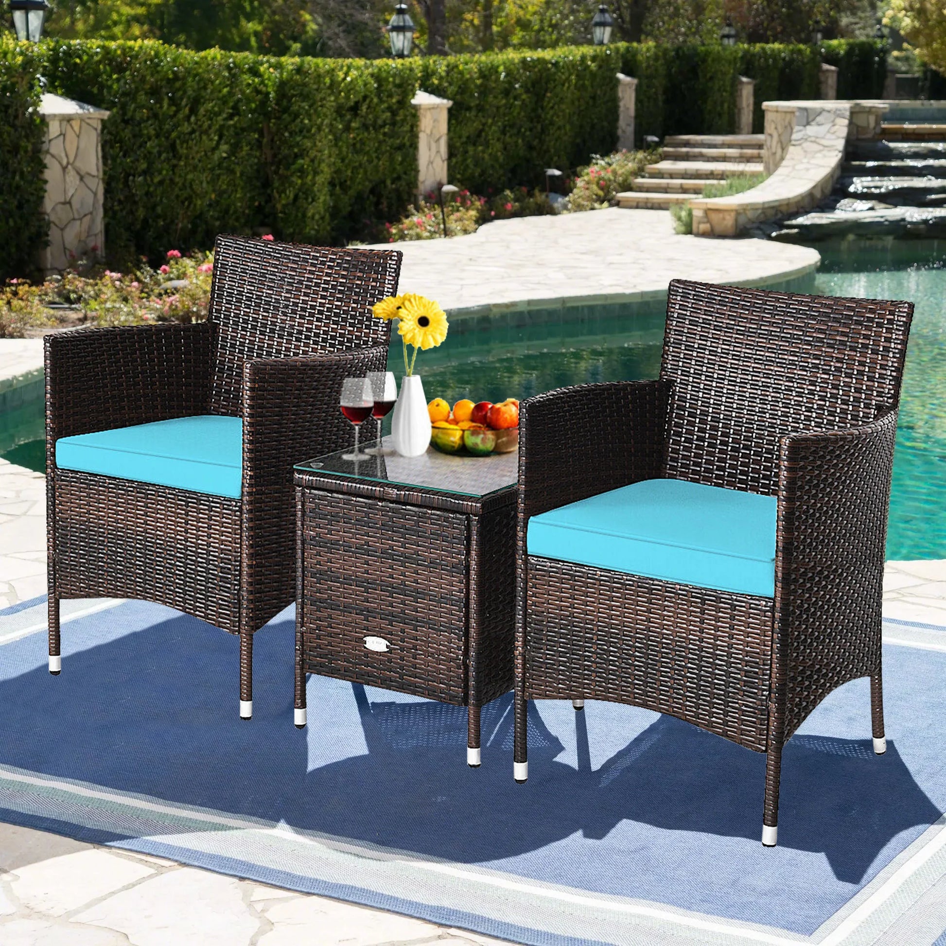 Outdoor Patio Chairs and Table Set | Brown/Teal from AHF Depot - Modern brown rattan frame patio conversation set with teal blue cushions and small glass top table adorned with fruit and glasses of wine, set amidst a sunny poolside scene.