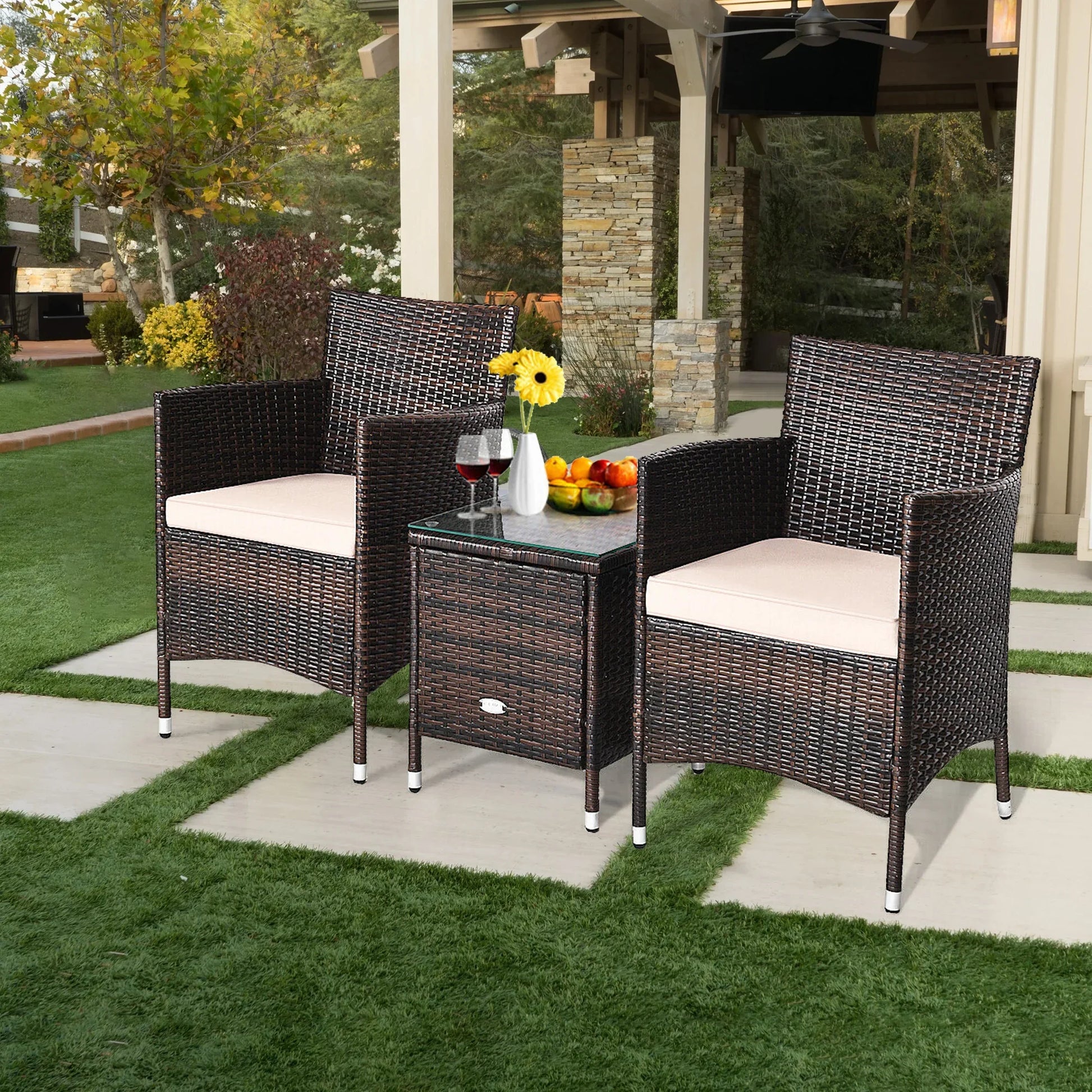 Outdoor Patio Chairs and Table Set | Brown/Tan from AHF Depot - Modern brown rattan frame patio conversation set with tan cushions and small glass top table adorned with fruit and glasses of wine, set amidst a sunny front yard scene.