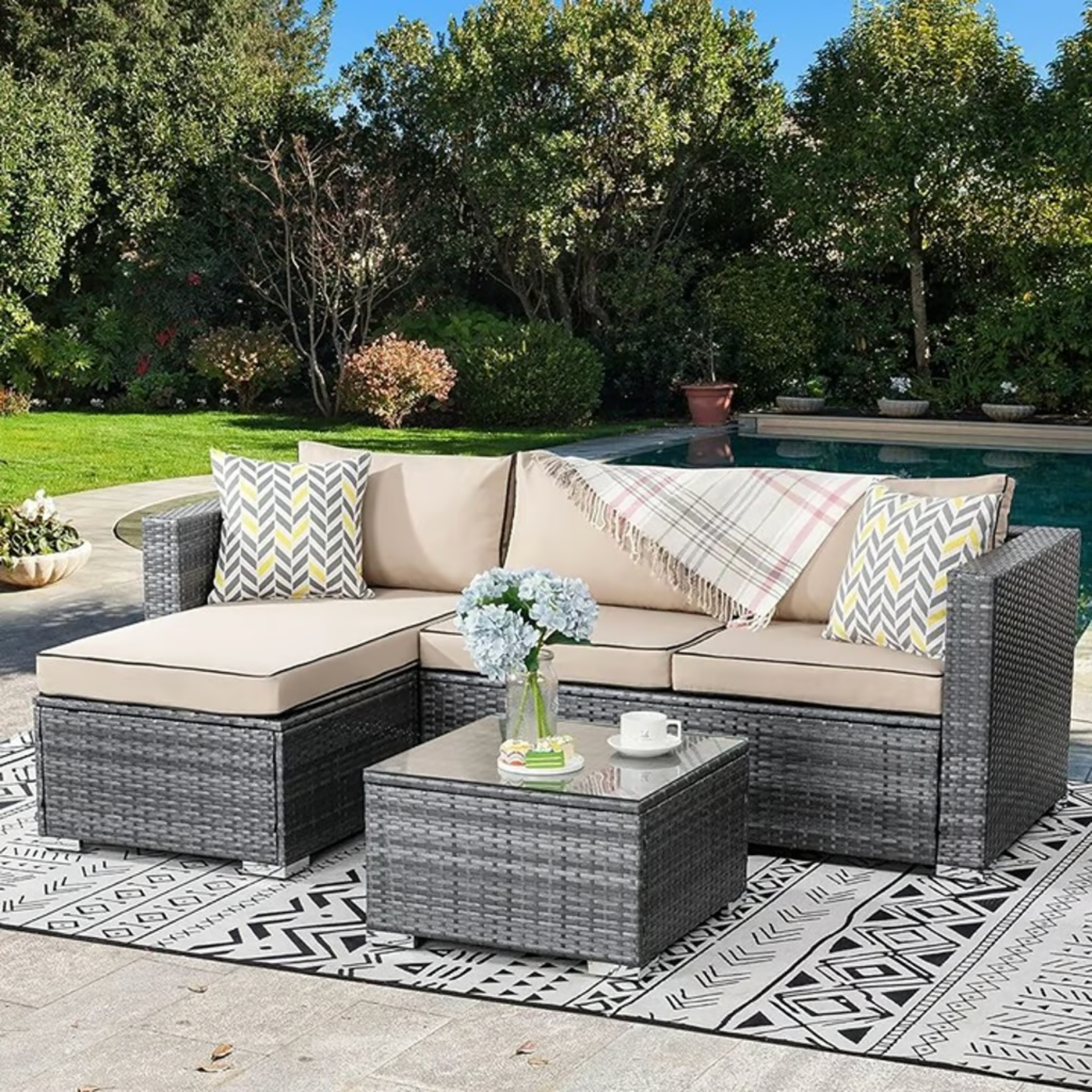 Outdoor Patio Sofa Set with Table | Grey/Tan from AHF Depot - Grey sectional couch with tan cushions and a small glass top table, complemented by a vase of flowers, set against a sunny poolside backdrop.