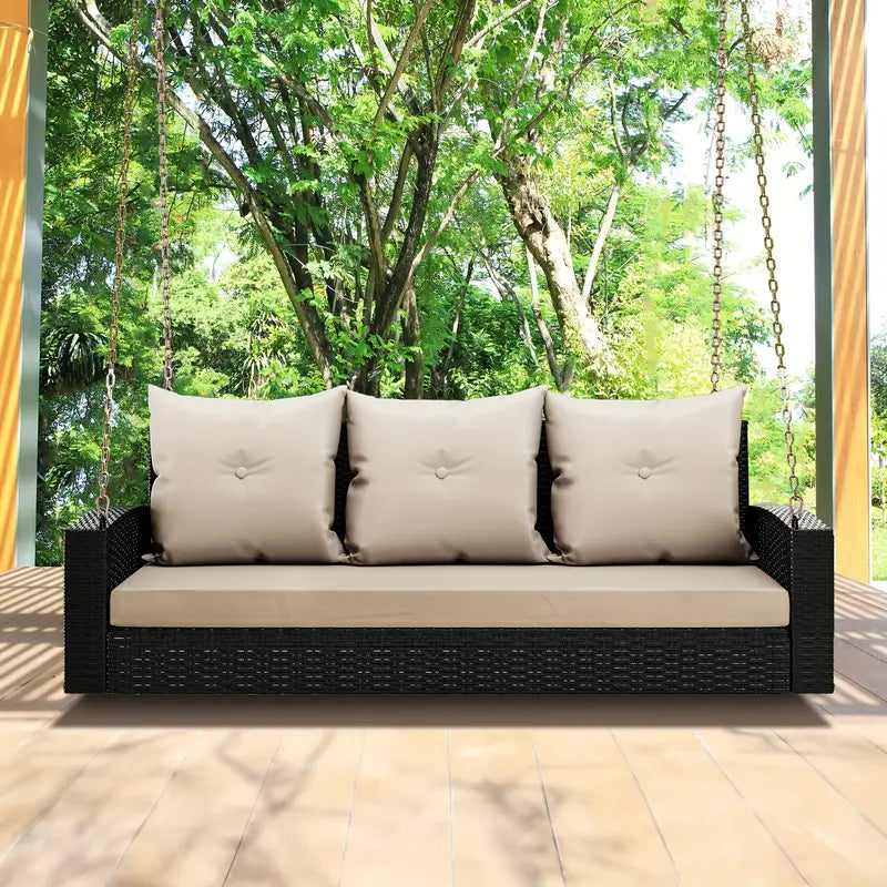 Outdoor Padded Porch Swing Hanging 3 Seater Chair | Black/Tan from AHF Depot - Modern black rattan frame hanging porch swing with tan cushions set against a sunny outdoor patio setting.